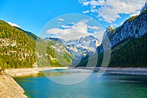 Beautiful Gosausee lake landscape with Dachstein mountains, forest, clouds and reflections in the water in Austrian Alps