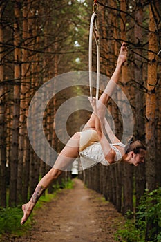 Beautiful and graceful aerial gymnast does exercises on the ring