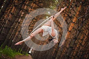 Beautiful and graceful aerial gymnast performs exercises on the air ring
