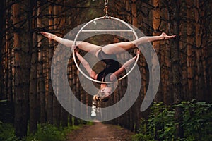 Beautiful and graceful aerial gymnast performs exercises on the air ring