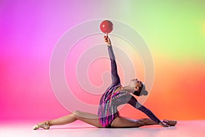 Beautiful, graceful sport. Young sportive girl, rhythmic gymnast in twine with red ball isolated on colored neon