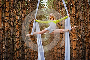 Beautiful and graceful trapeze artist performs exercises on aerial silk