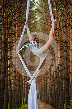 Beautiful and graceful trapeze artist performs exercises on aerial silk