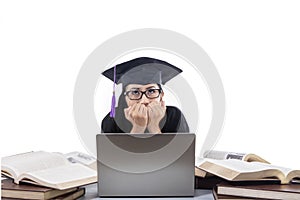 Beautiful graduate afraid in front of laptop