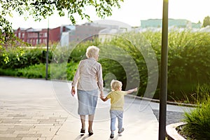 Beautiful granny and her little grandchild walking together in park