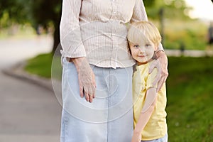 Beautiful granny and her little grandchild walking together in park