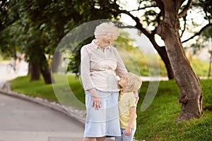 Beautiful granny and her little grandchild walking together in park