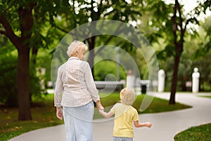 Beautiful granny and her little grandchild walking together in park