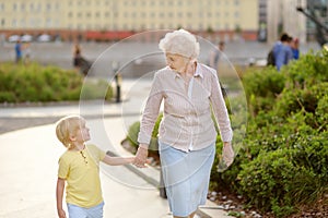 Beautiful granny and her little grandchild walking together in park