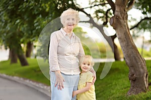 Beautiful granny and her little grandchild walking together in park