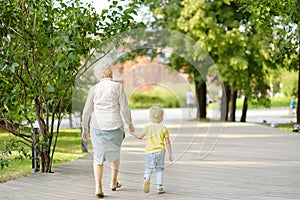 Beautiful granny and her little grandchild walking together in park