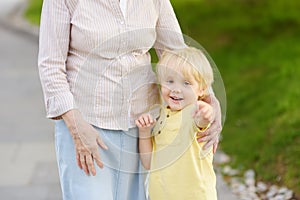 Beautiful granny and her little grandchild walking together in park