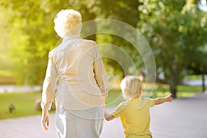 Beautiful granny and her little grandchild walking together in park