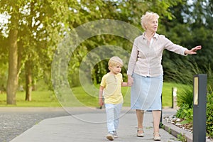 Beautiful granny and her little grandchild walking together in park