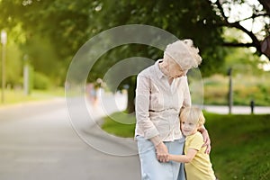 Beautiful granny and her little grandson walking together in park