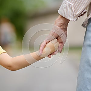 Beautiful granny and her little grandson walking together in park