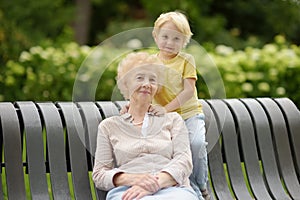 Beautiful granny and her little grandson walking together in park