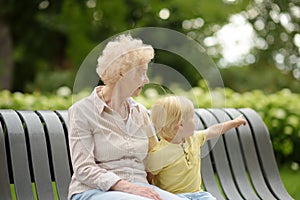 Beautiful granny and her little grandson walking together in park