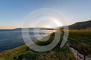 Beautiful grass covered beach by the calm ocean under the sunset capture in Samos, Greece