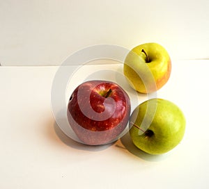 A great composition of three fresh and shiny green, red and yellow apples on a triangular composition on a white background