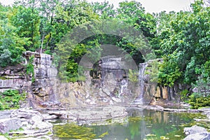 Beautiful green botanical landscape design in garden, city park with trees, bushes and waterfall, decorative lake pond