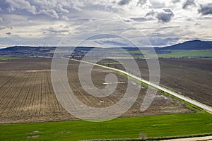 beautiful green countryside, fields, road, and cloudy sky