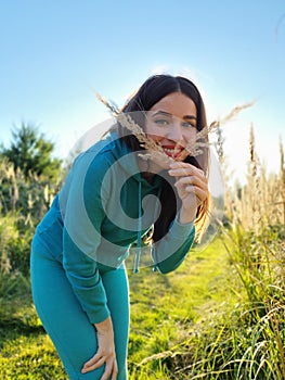 A beautiful girl in a field playing with plants. The concept of walking in nature, freedom and an eco-friendly lifestyle