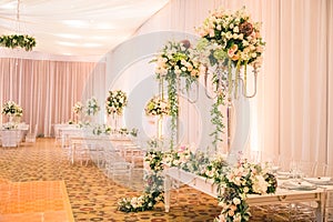 BEAUTIFUL GREEN FLORAL DECORATION AT WHITE GROOM AND BRIDE WEDDING TABLE WITH IMPRESSIVE COLOURFUL VENUE, CARPET FLOOR AND BLURRED