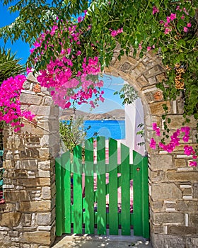 Beautiful green gate and stone arch with flowers, entrance door, romantic greek style, cycladic islands greece
