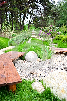 Beautiful green landscape design, botanic garden park with decorative flower bed with pebbles, stones, trees, bushes