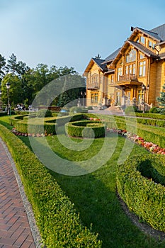 Beautiful green lawn framed by bushes and flowers in front of a large rich mansion, the residence of Yanukovych Museum