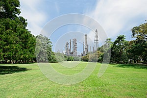 Beautiful green park with oil refinery and smokestack in background