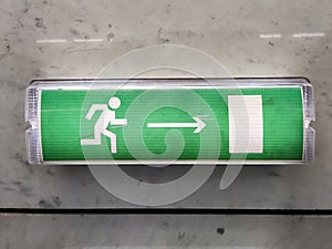 a beautiful green sign with a bright emergency exit light hanging on the wall. Index of escape routes