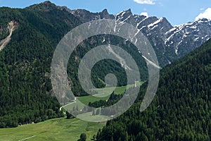 Beautiful green valley with covered snow mountain peaks