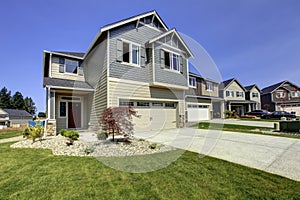 Beautiful grey house exterior with stone, green lawn and driveway.