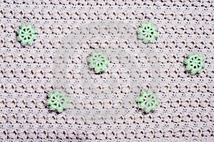 Beautiful grey knitted texture. Elegant pattern with elaborately bound and sewn green flowers. Crochet close-up. background for photo