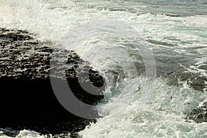 Beautiful grey sea stormy waves splash against black stony shore