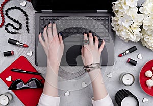 Beautiful groomed woman`s hands typing at keyboard on the home office table