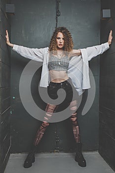 Beautiful grunge woman with torn tights and cutly hair standing in the studio