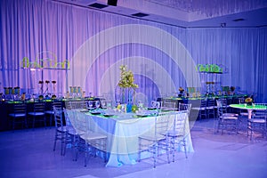 Beautiful guest square table set up for a wedding or social event in the ballroom orchid and lucite chairs draped walls photo