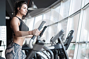 Beautiful gym woman exercising on a cardio machine smiling.