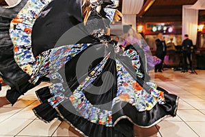 Beautiful gypsy girls dancing in traditional black floral dress at wedding reception in restaurant. Woman performing romany dance