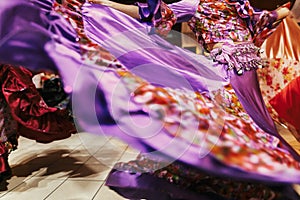 Beautiful gypsy girls dancing in traditional purple floral dress at wedding reception in restaurant. Woman performing romany dance