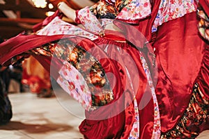 Beautiful gypsy girls dancing in traditional red floral dress at wedding reception in restaurant. Woman performing romany dance