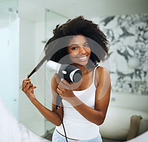 Beautiful hair requires proper care. Portrait of an attractive young woman blowdrying her hair at home.