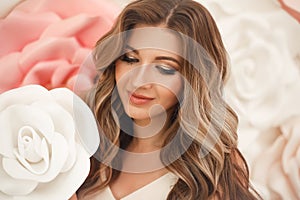 Beautiful hair. Woman beauty portrait smiling with makeup and long healthy hairstyle over pink white roses flowers