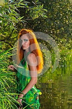 Beautiful half dressed red hair woman enjoys the waters of river