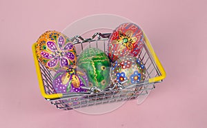Beautiful hand painted Easter eggs in a basket from the supermarket on a pink background