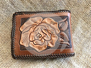 Beautiful Hand Tooled Leather Wallet with Lacing and Rose Design On Burlap Background