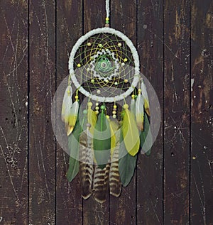 Beautiful handmade boho dreamcatcher with green, yellow and white feathers and medalion